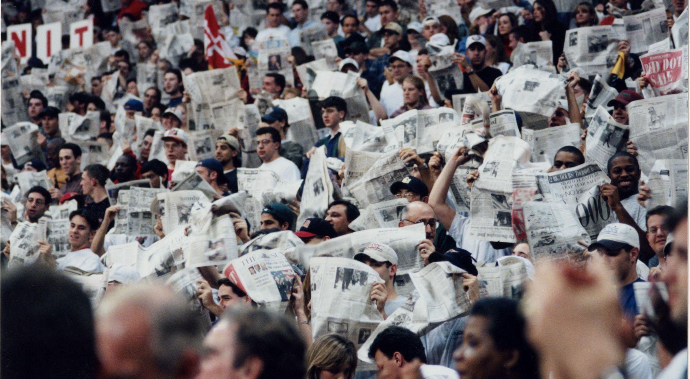 Students holding newspapers up during a game