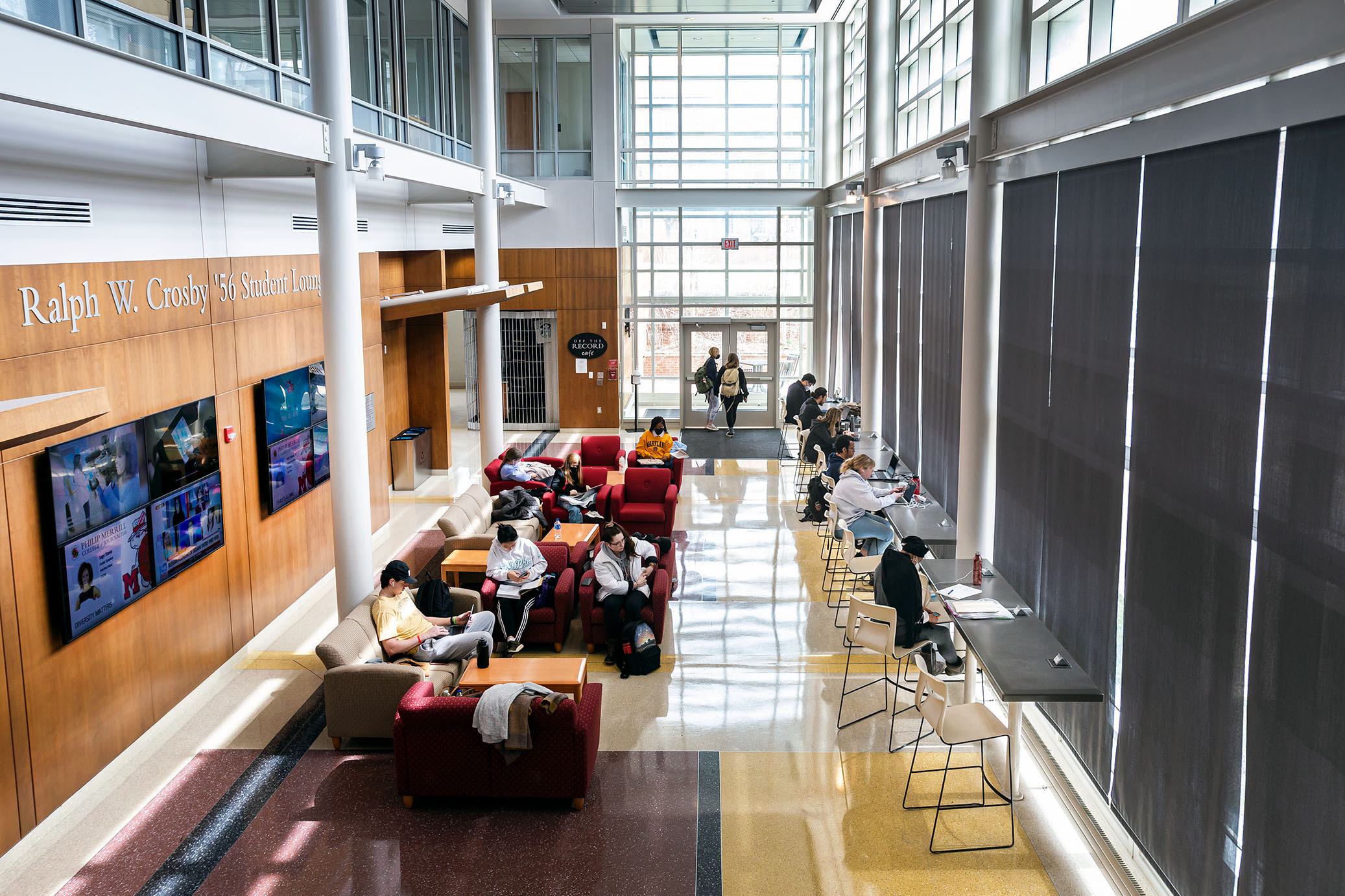 Students in the lobby area of Knight Hall, brightly illuminated by sunlight from the many surrounding windows.