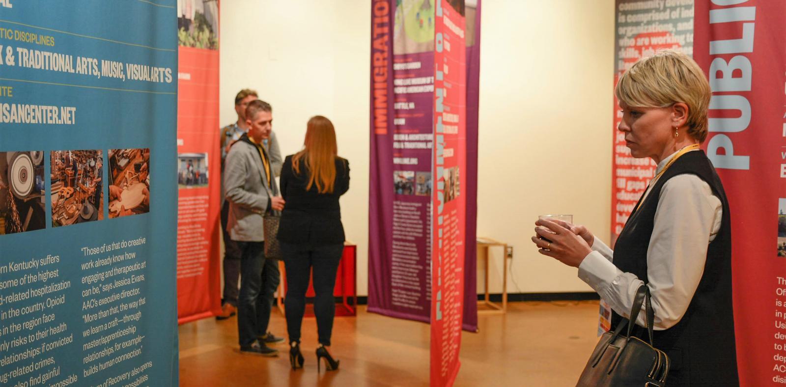 Visitors looking at banners in an exhibition. Writing and photos on banners