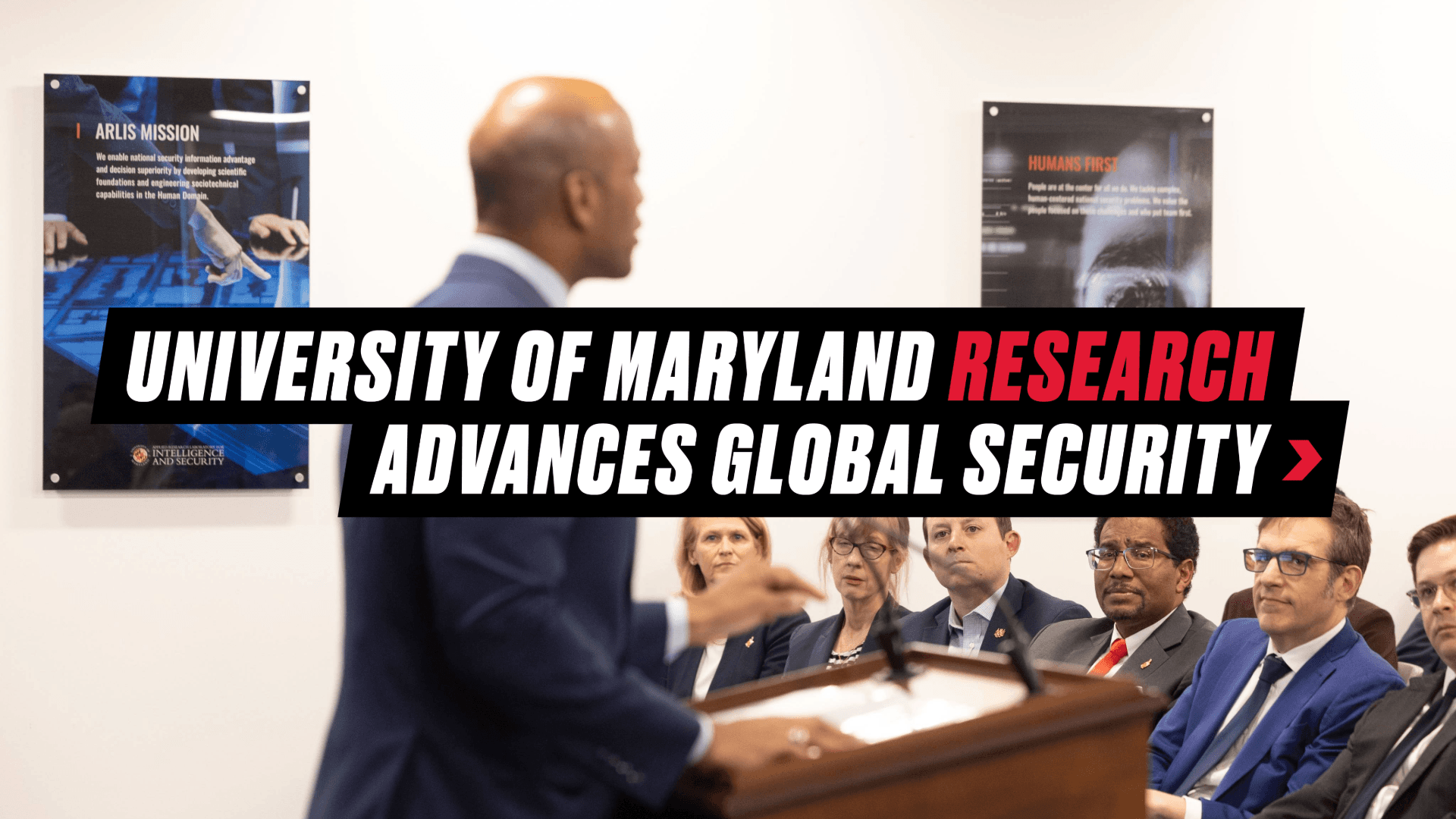 Graphic reading "University of Maryland Research Advances Global Security" with a background image of Governor Wes Moore speaking to UMD and DOD researchers and leadership