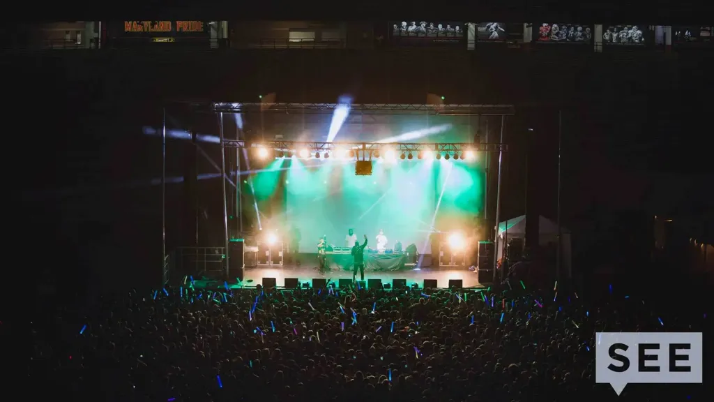 Lit stage with performer. Packed audience.