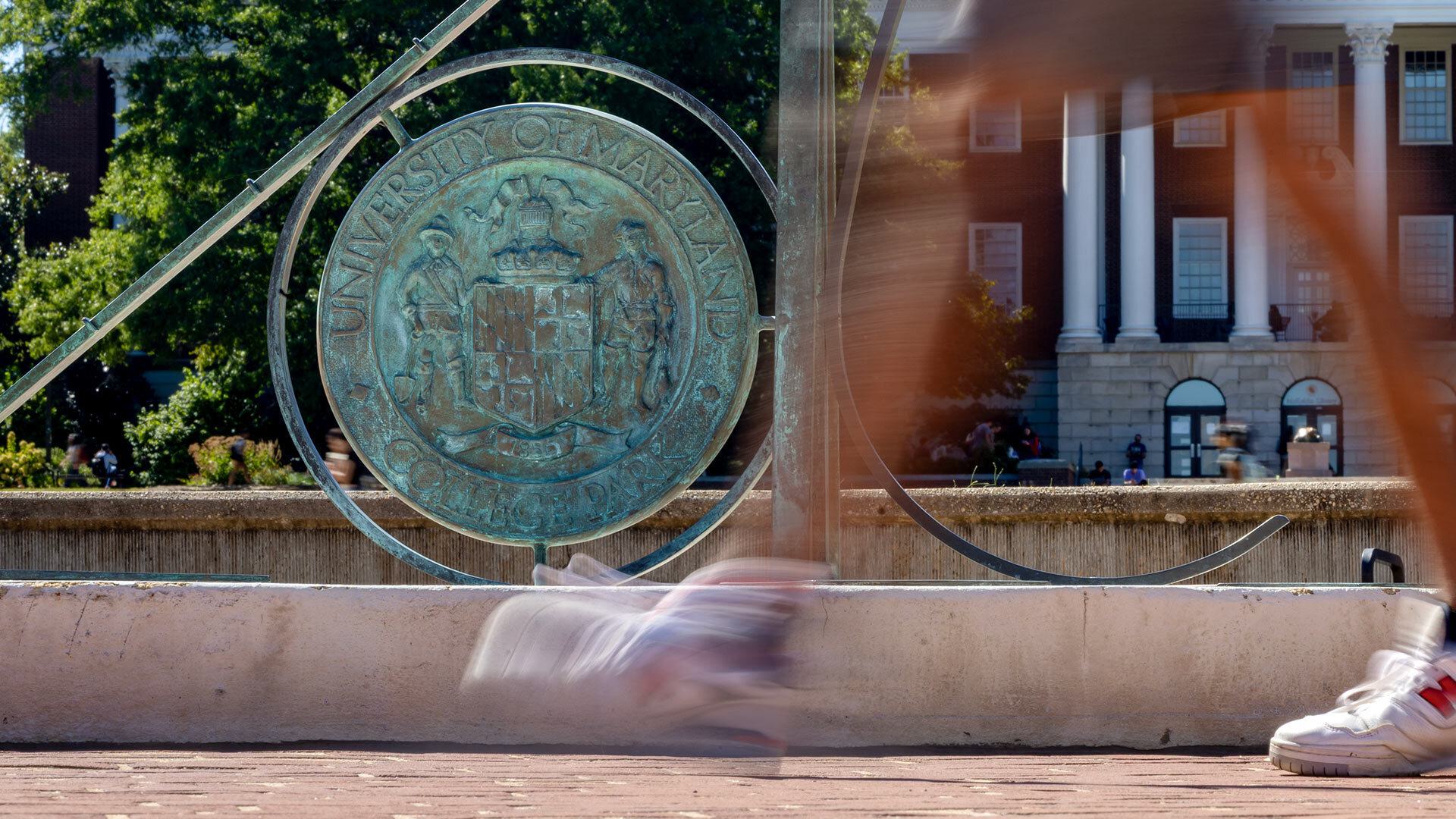 closeup of student walking past sundial on McKeldin Mall