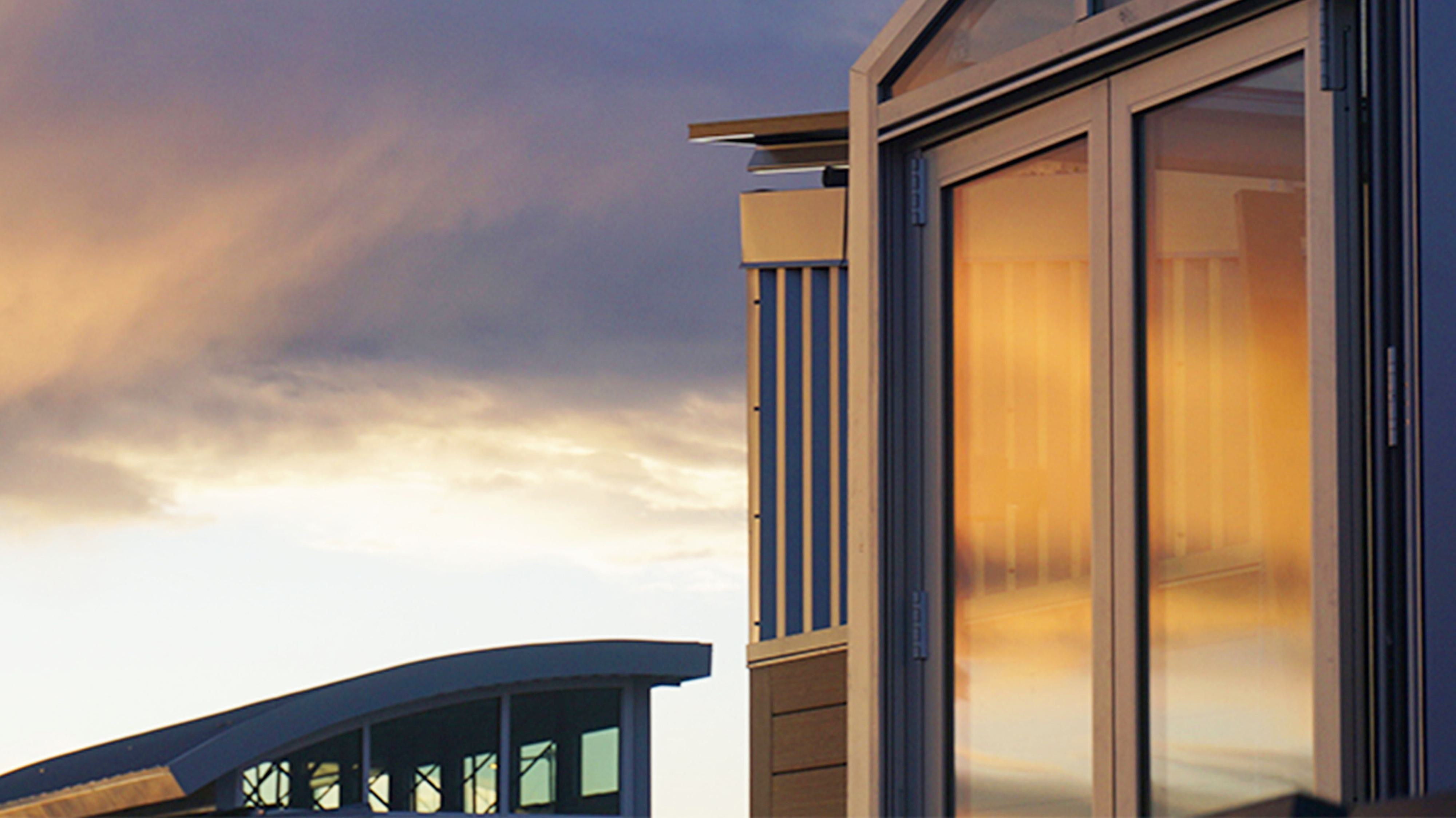 Gray, blue, and golden clouds reflected in a building's windows