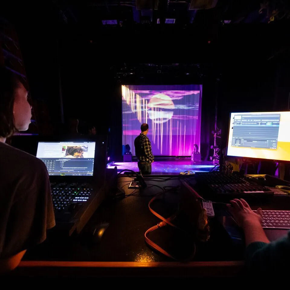 students at computers observing a theater set/performance