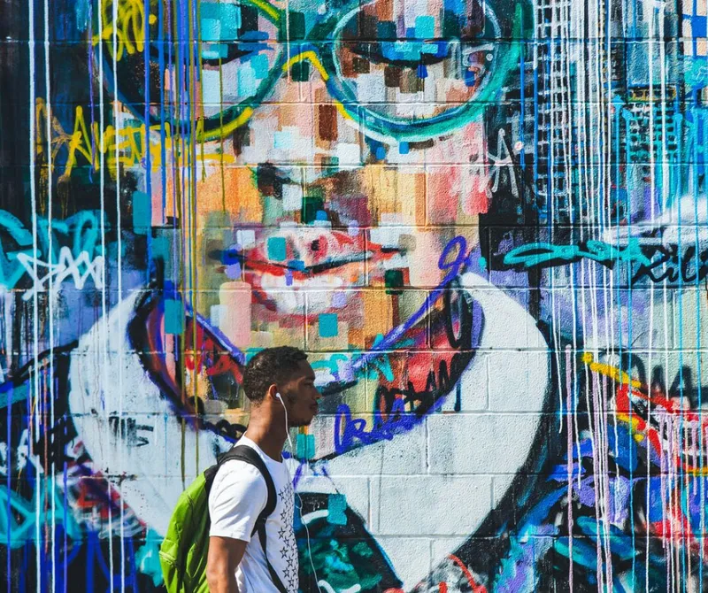 Student walking in front of a mural of a large close up face