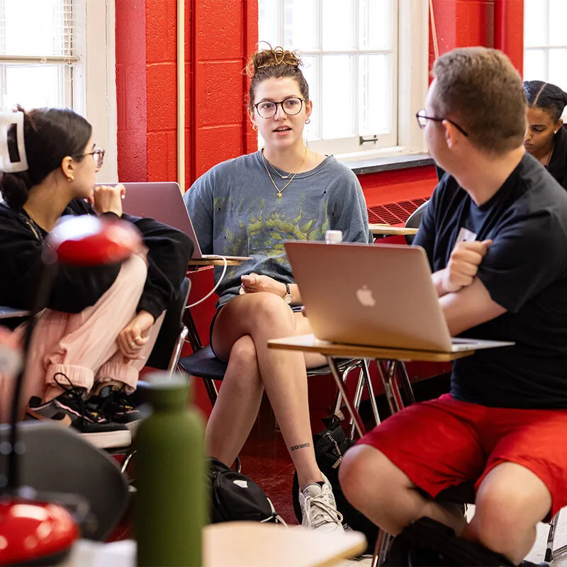 Group of students having a discussion in a classroom with red walls