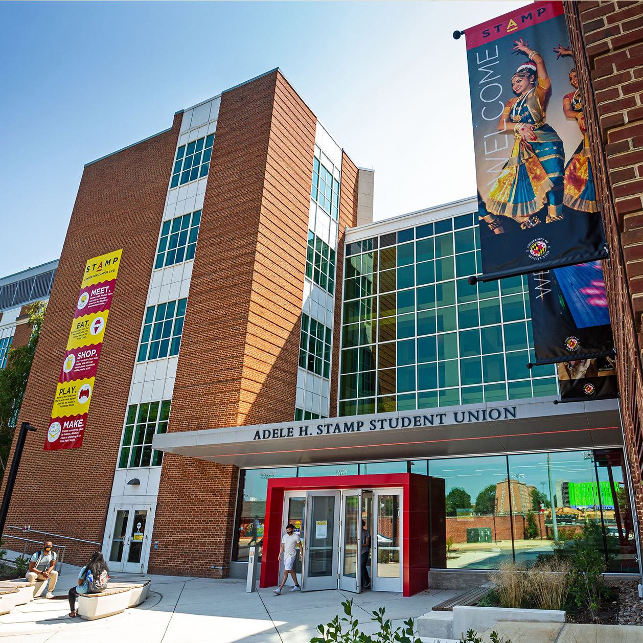Outside of Adele H. Stamp Student Union building. Large building with banners and a students walking outside