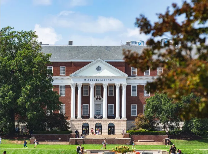 Bright blue skies, above students out and about along lush green lawns, and sun washed red brick