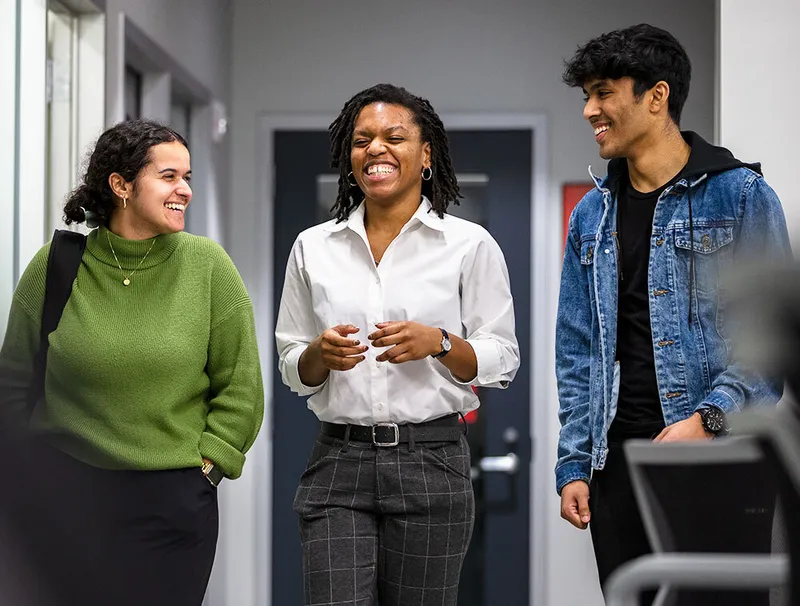 Students standing, talking, laughing in a hallway.